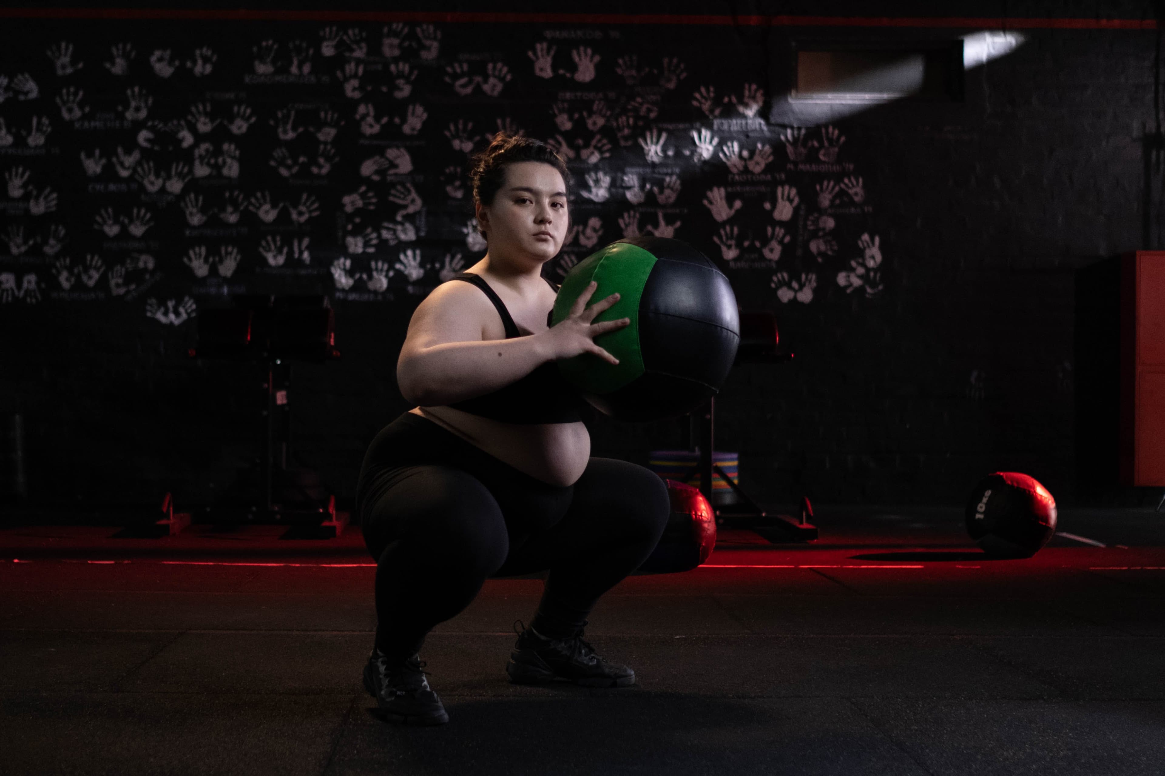 Professional personal trainer demonstrating proper form with dumbbells in modern gym setting